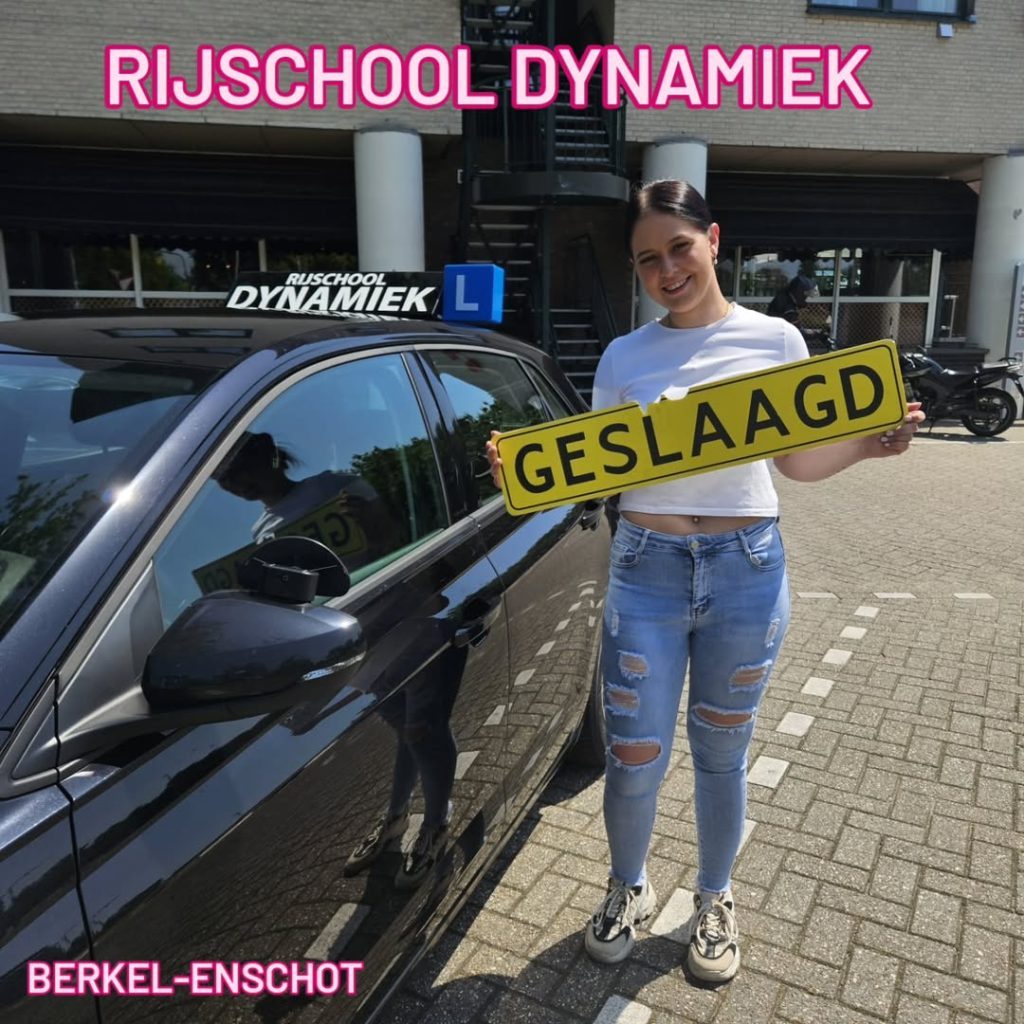 #RijschoolDynamiek #rijbewijsgehaald #geslaagdrijbewijs #besterijschooltilburg #rijlestilburg Een geslaagde leerling staat naast een lesauto met een 'GESLAAGD' bord in haar hand